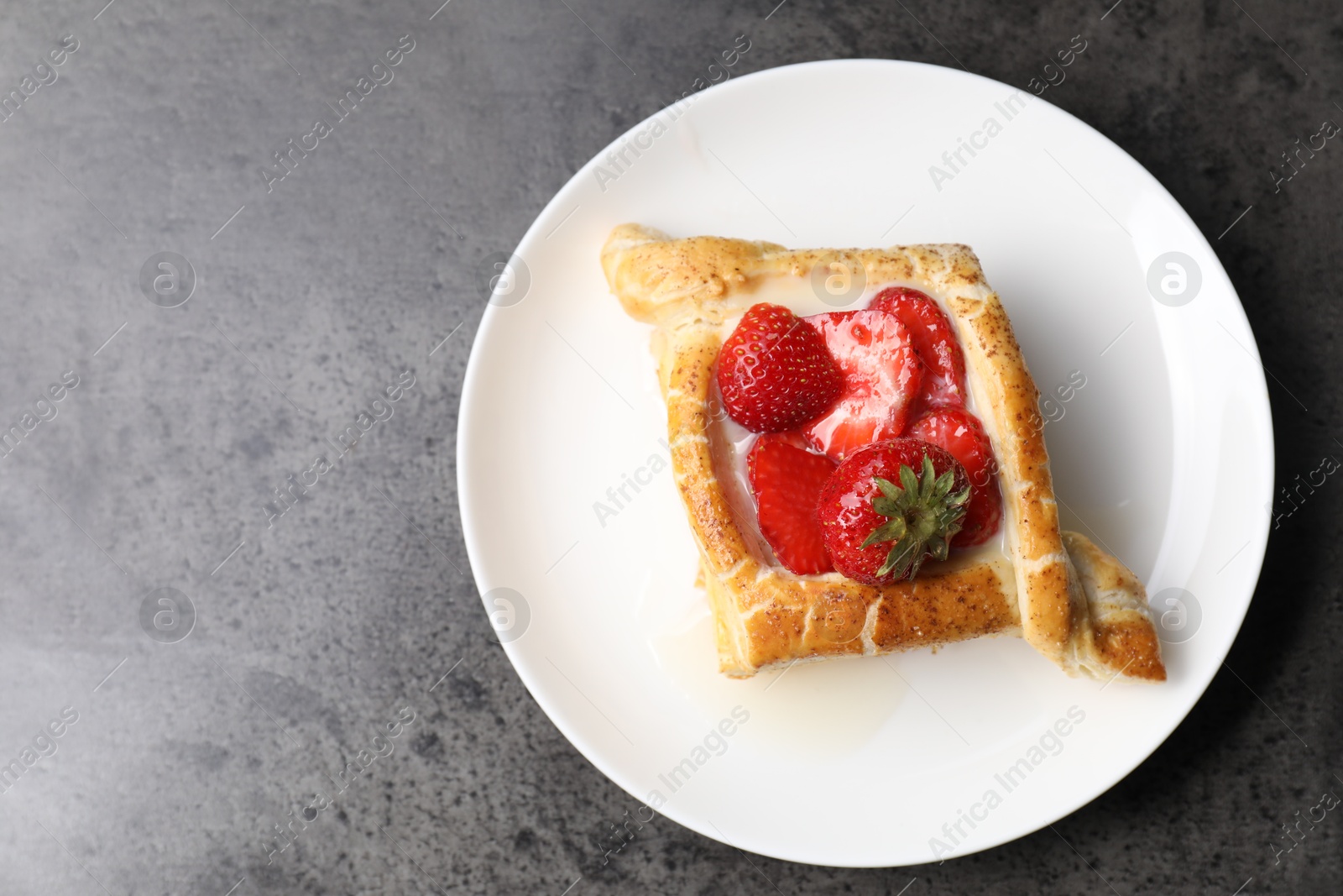 Photo of Tasty puff pastry with strawberries on grey table, top view. Space for text