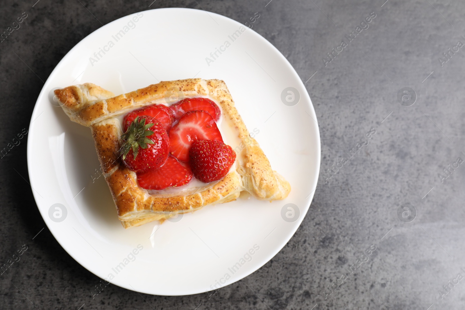 Photo of Tasty puff pastry with strawberries on grey table, top view. Space for text