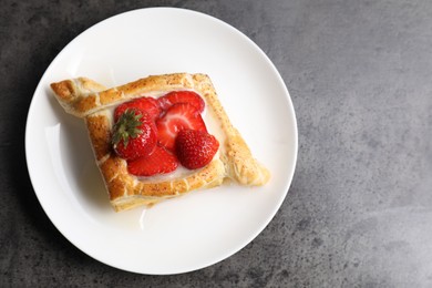 Tasty puff pastry with strawberries on grey table, top view. Space for text