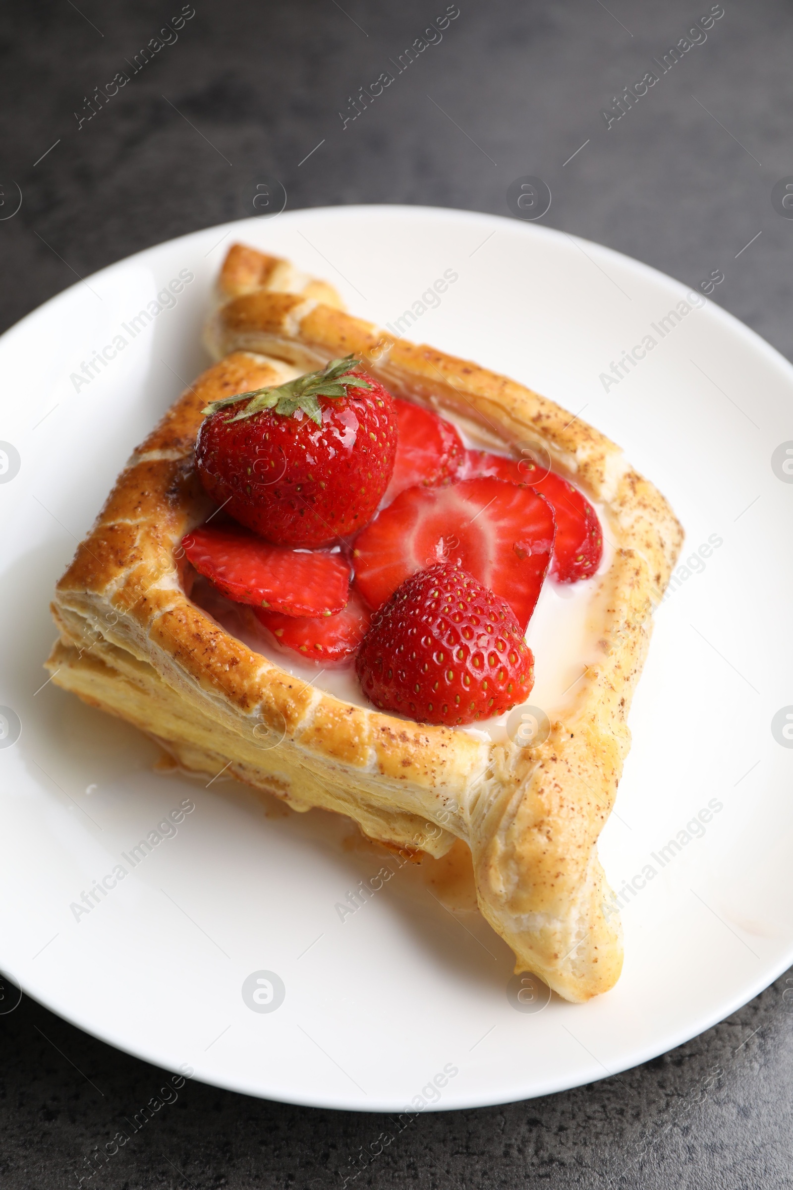 Photo of Tasty puff pastry with strawberries on grey table, closeup