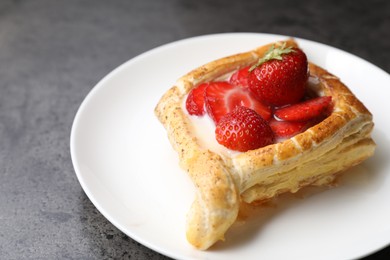 Photo of Tasty puff pastry with strawberries on grey table, closeup