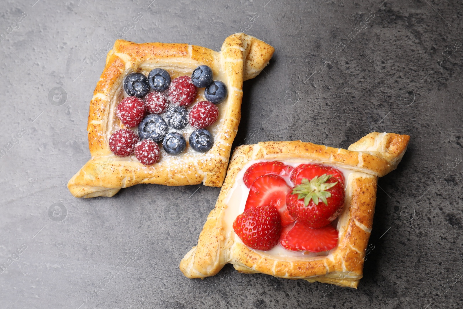 Photo of Tasty puff pastries with berries on grey table, top view