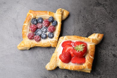 Tasty puff pastries with berries on grey table, top view