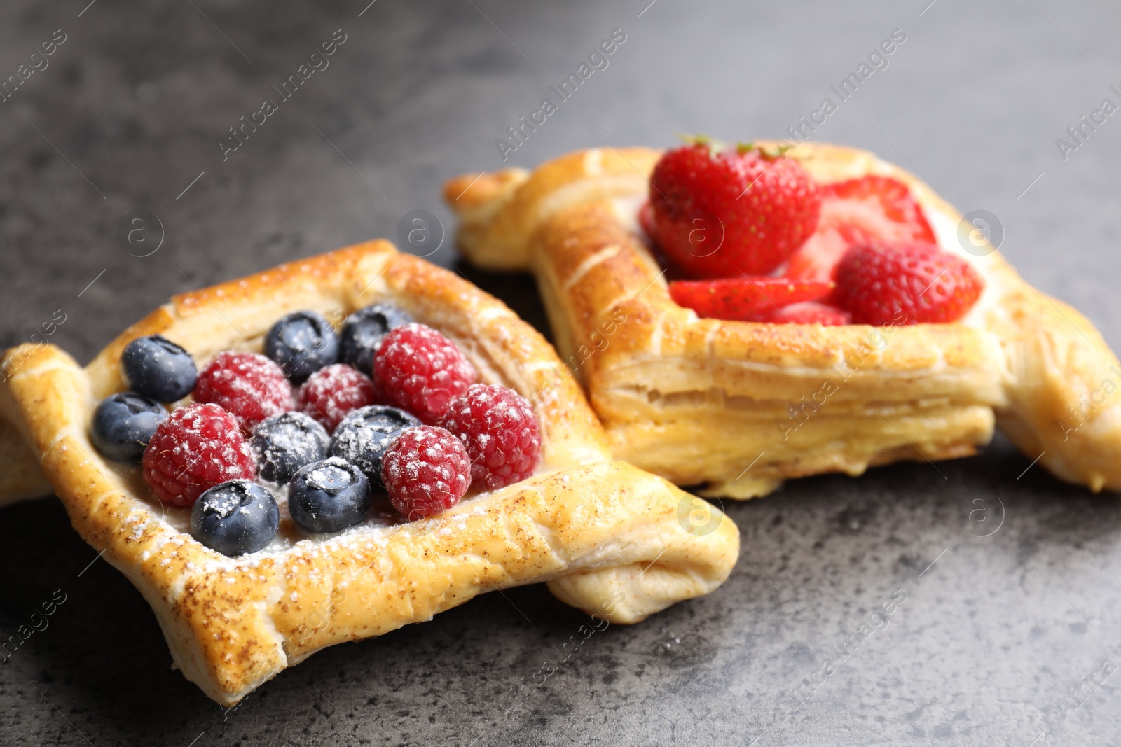 Photo of Tasty puff pastries with berries on grey table, closeup