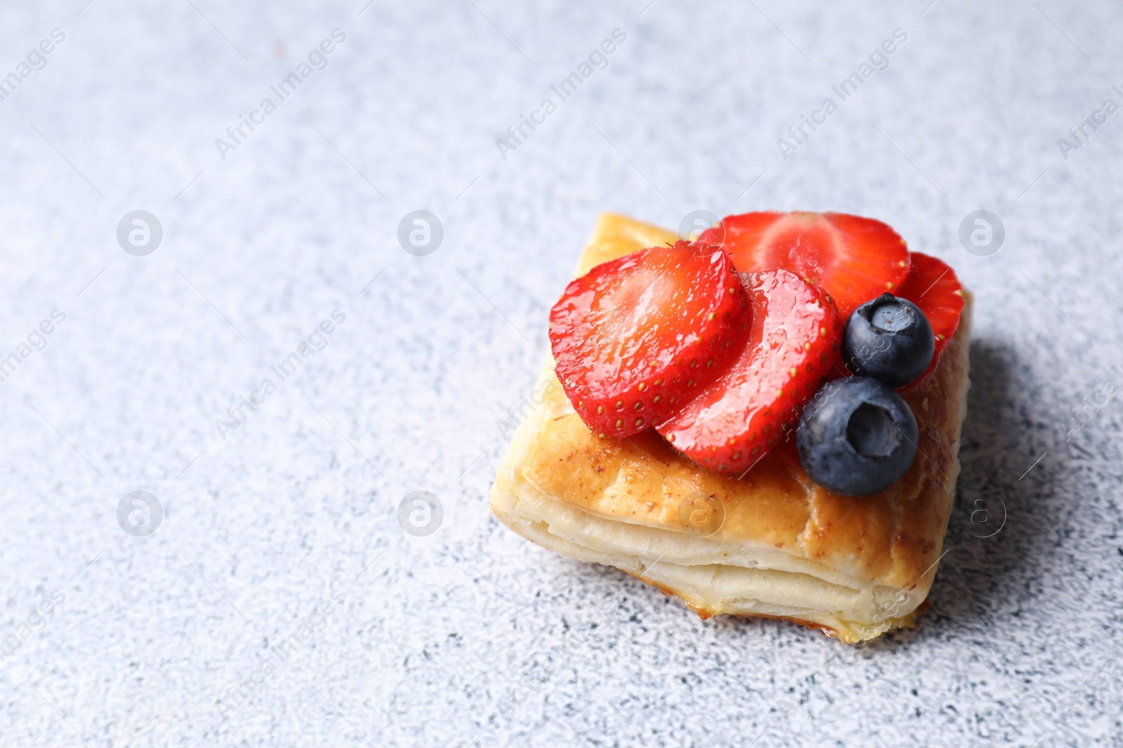 Photo of Tasty puff pastry with berries on light grey table, space for text