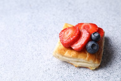 Photo of Tasty puff pastry with berries on light grey table, space for text