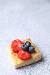 Tasty puff pastry with berries on light grey table, space for text