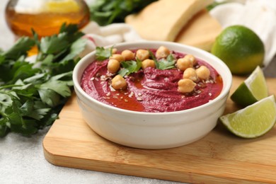 Photo of Tasty beet hummus with chickpeas and parsley in bowl on light table