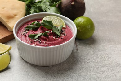 Photo of Tasty beet hummus with sesame and lime in bowl on grey textured table