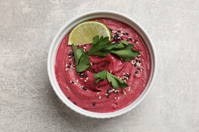 Photo of Tasty beet hummus with sesame and lime in bowl on grey textured table, top view