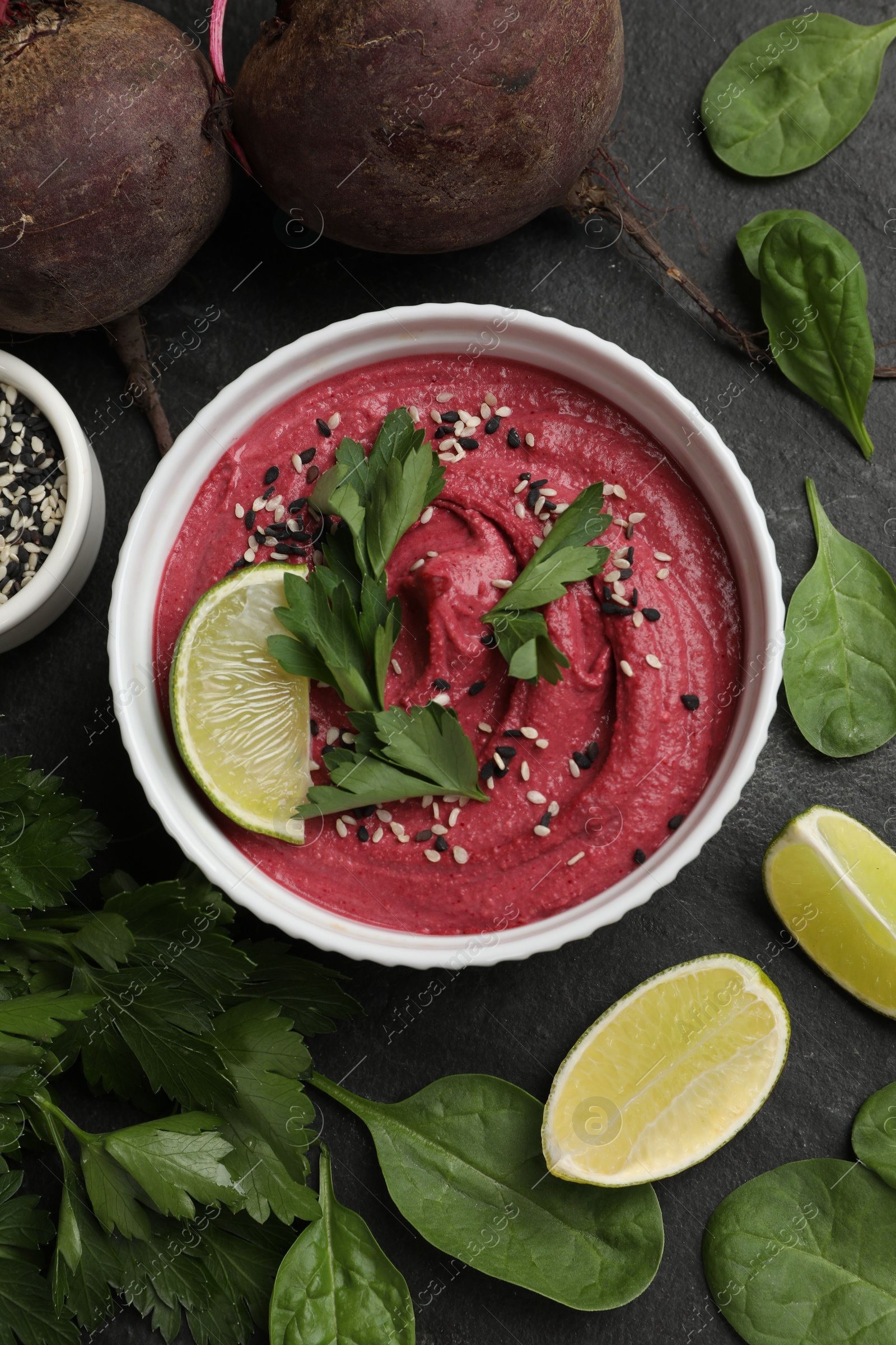 Photo of Tasty beet hummus in bowl and fresh ingredients on grey textured table, flat lay