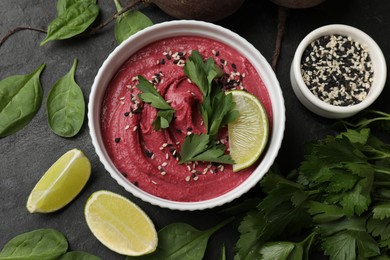 Photo of Tasty beet hummus in bowl and fresh ingredients on grey textured table, flat lay