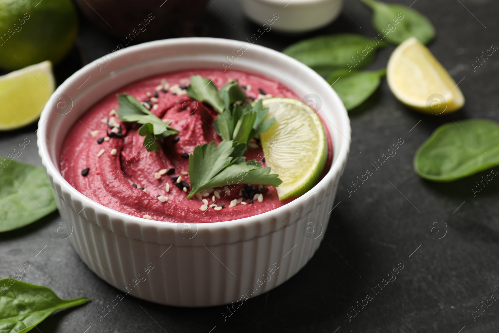 Photo of Tasty beet hummus with sesame and parsley in bowl on grey table, closeup