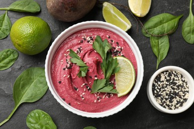 Tasty beet hummus in bowl and fresh ingredients on grey textured table, flat lay