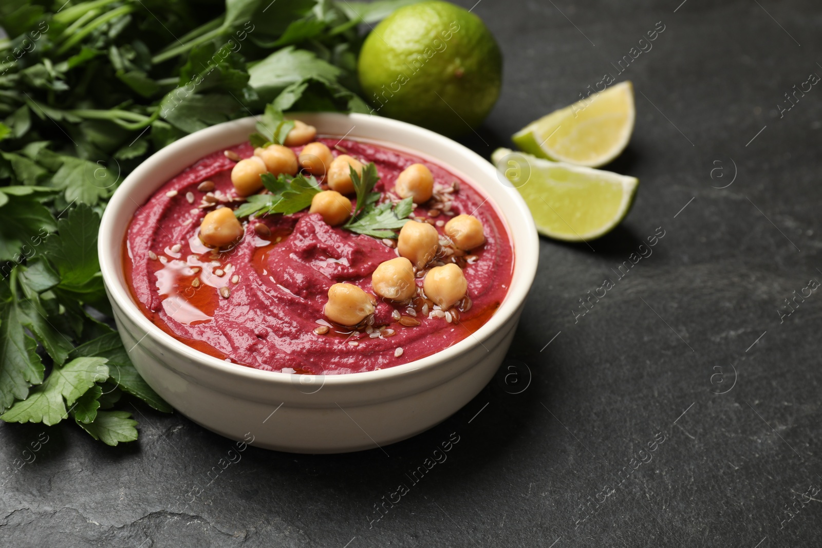 Photo of Tasty beet hummus with chickpeas in bowl on grey textured table