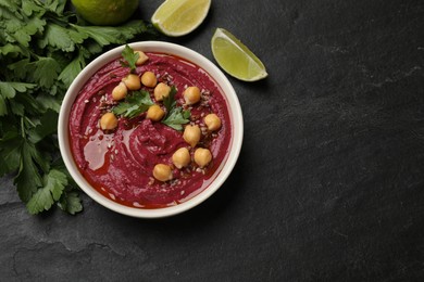 Photo of Tasty beet hummus with chickpeas in bowl, lime and parsley on grey textured table, flat lay. Space for text