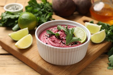 Photo of Tasty beet hummus with lime and parsley in bowl on wooden table