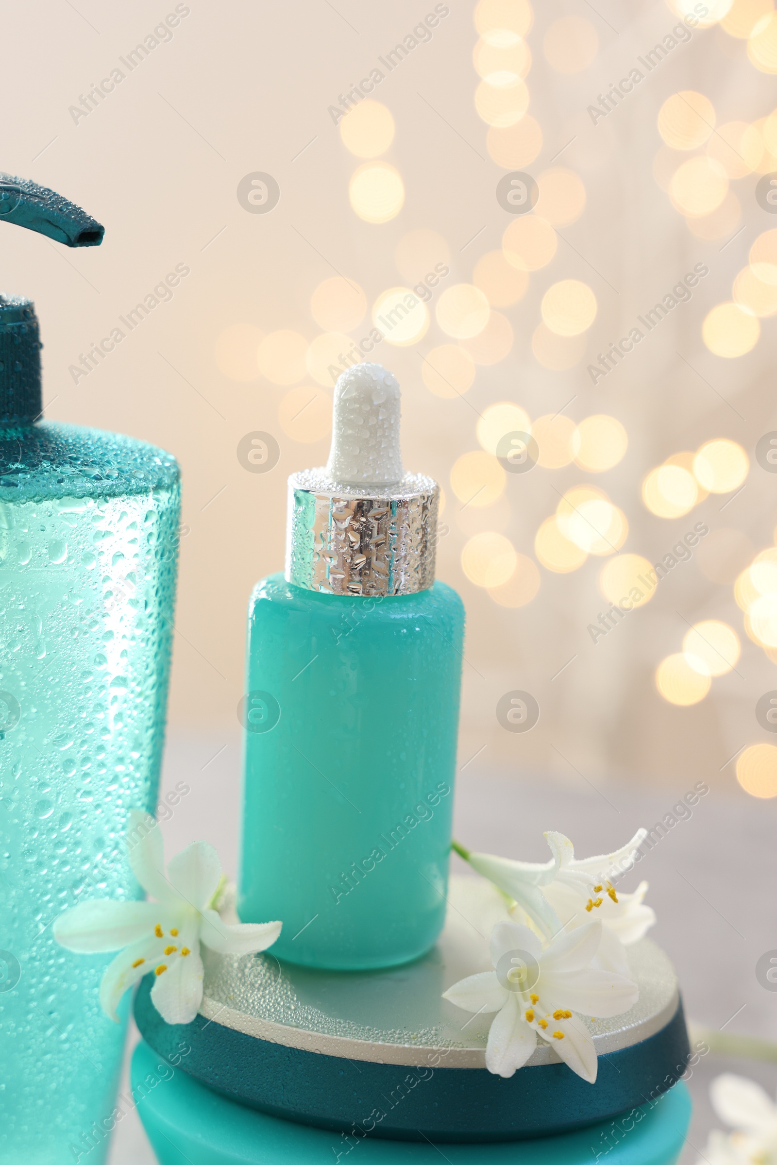 Photo of Cosmetic products and jasmine flowers against beige background with blurred lights, closeup