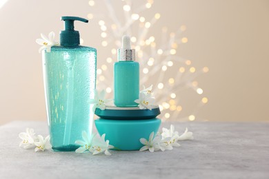 Photo of Cosmetic products and beautiful jasmine flowers on grey table