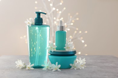 Photo of Cosmetic products and beautiful jasmine flowers on grey table