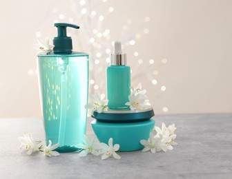 Cosmetic products and beautiful jasmine flowers on grey table