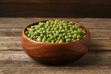 Fresh green peas in bowl on wooden table