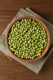 Photo of Fresh green peas in bowl on wooden table, top view