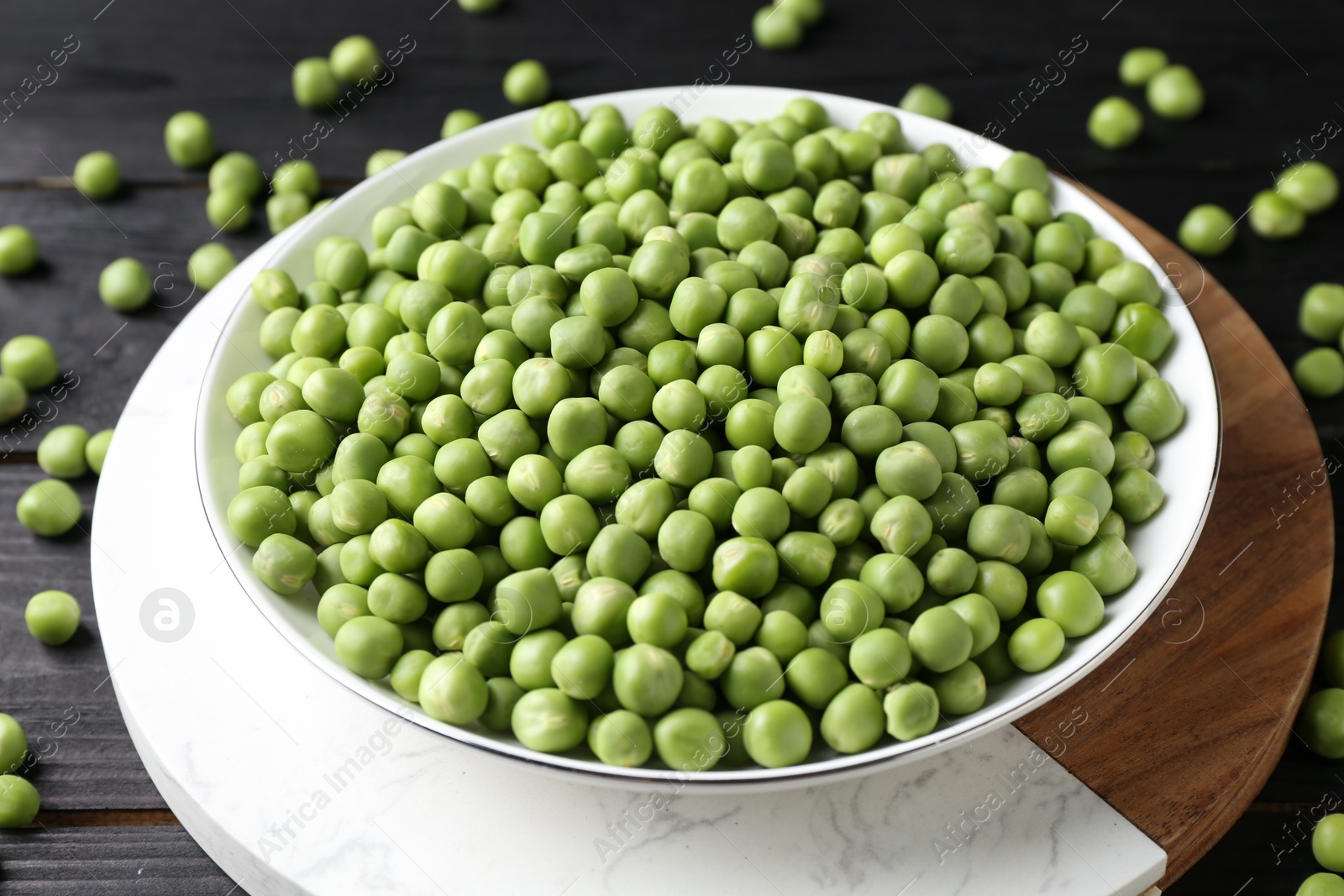 Photo of Fresh green peas in bowl on black wooden table, closeup