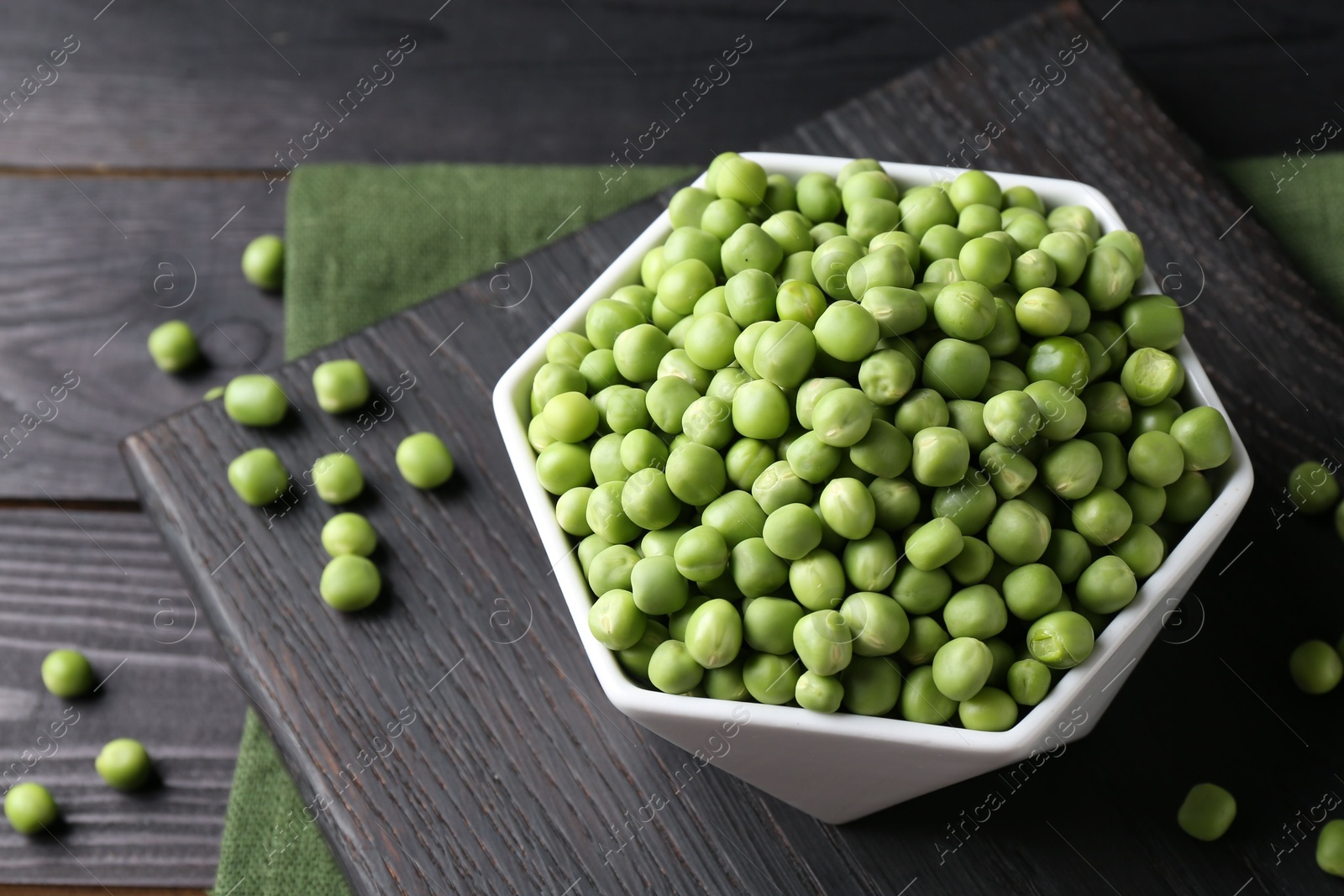 Photo of Fresh green peas in bowl on black wooden table