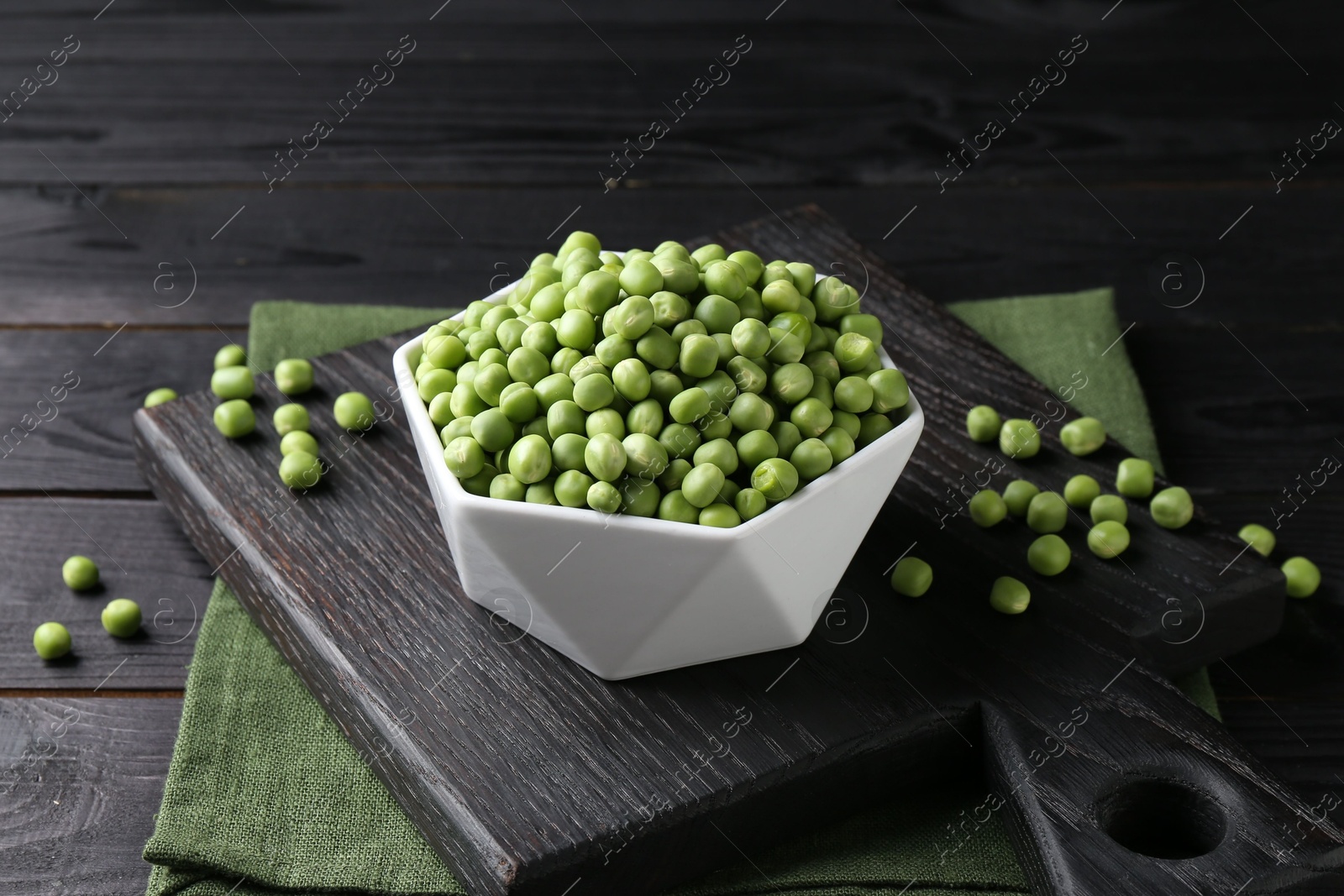 Photo of Fresh green peas in bowl on black wooden table