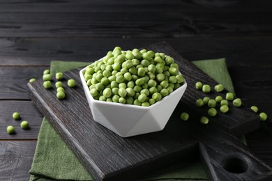 Fresh green peas in bowl on black wooden table