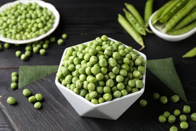 Fresh green peas in bowl on black wooden table