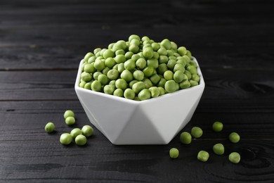 Fresh green peas in bowl on black wooden table