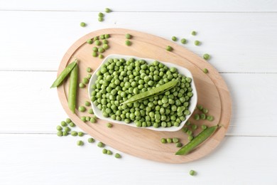 Photo of Fresh green peas and pods on white wooden table, flat lay