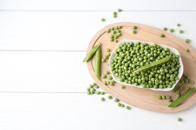 Fresh green peas and pods on white wooden table, flat lay. Space for text