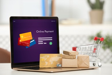 Image of Online payment system. Laptop with open application and small parcels on table