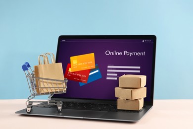 Image of Online payment system. Laptop with open application and small parcels on table