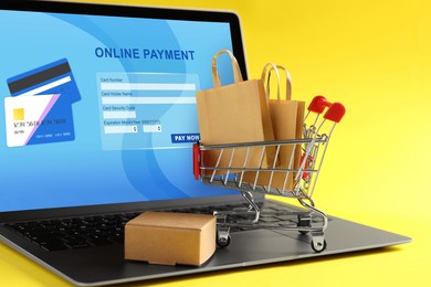 Image of Online payment system. Laptop with open application and small parcels on table