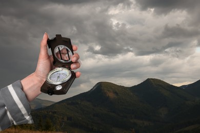 Image of Woman using compass in mountains, closeup. Navigational instrument