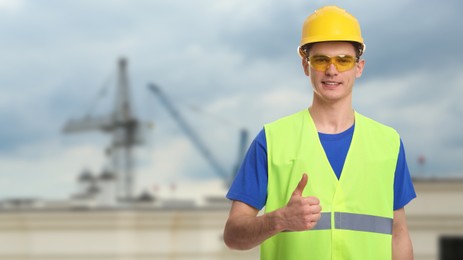 Image of Young man wearing safety equipment and showing thumbs up at construction site. Banner design with space for text