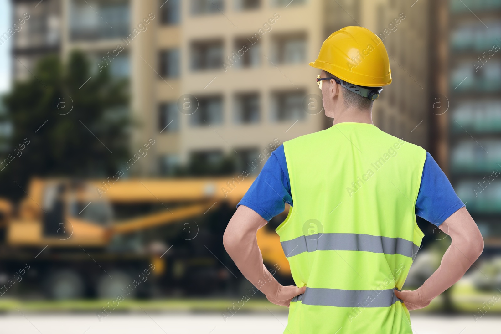 Image of Man wearing safety equipment at construction site, back view. Space for text