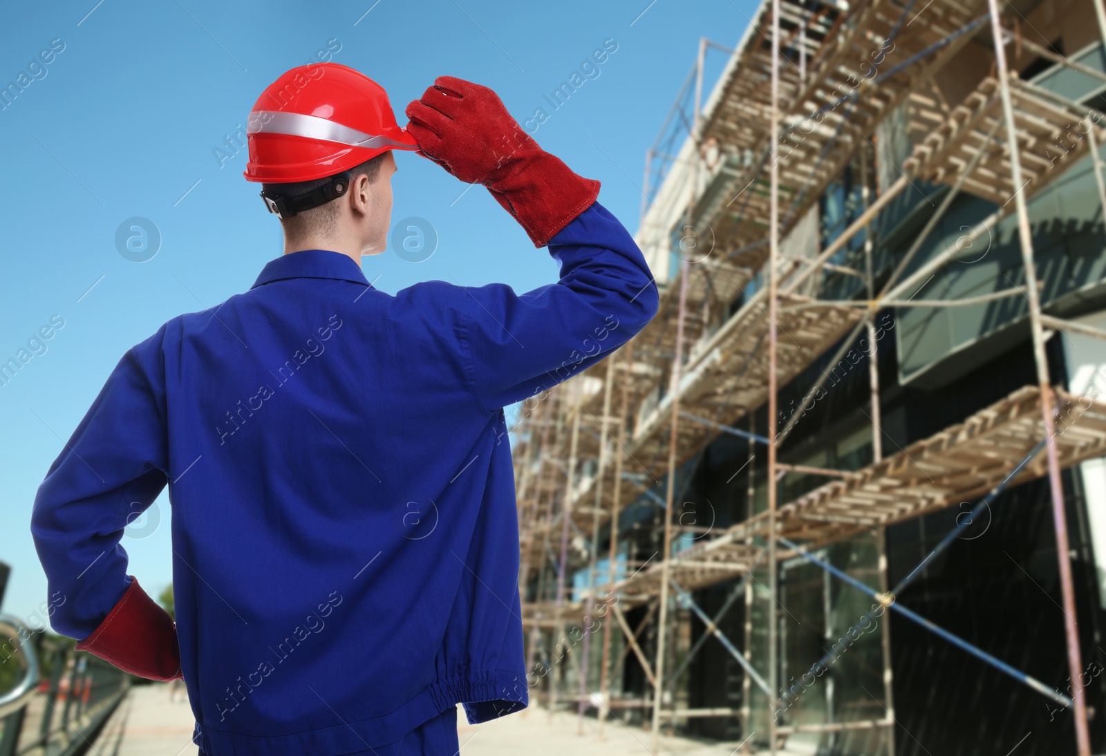 Image of Young man wearing safety equipment at construction site, back view. Space for text