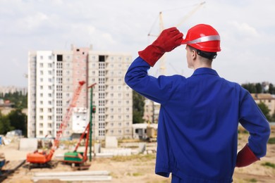 Image of Young man wearing safety equipment at construction site, back view. Space for text