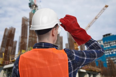 Image of Young man wearing safety equipment at construction site, back view