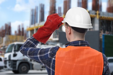 Image of Young man wearing safety equipment at construction site, back view