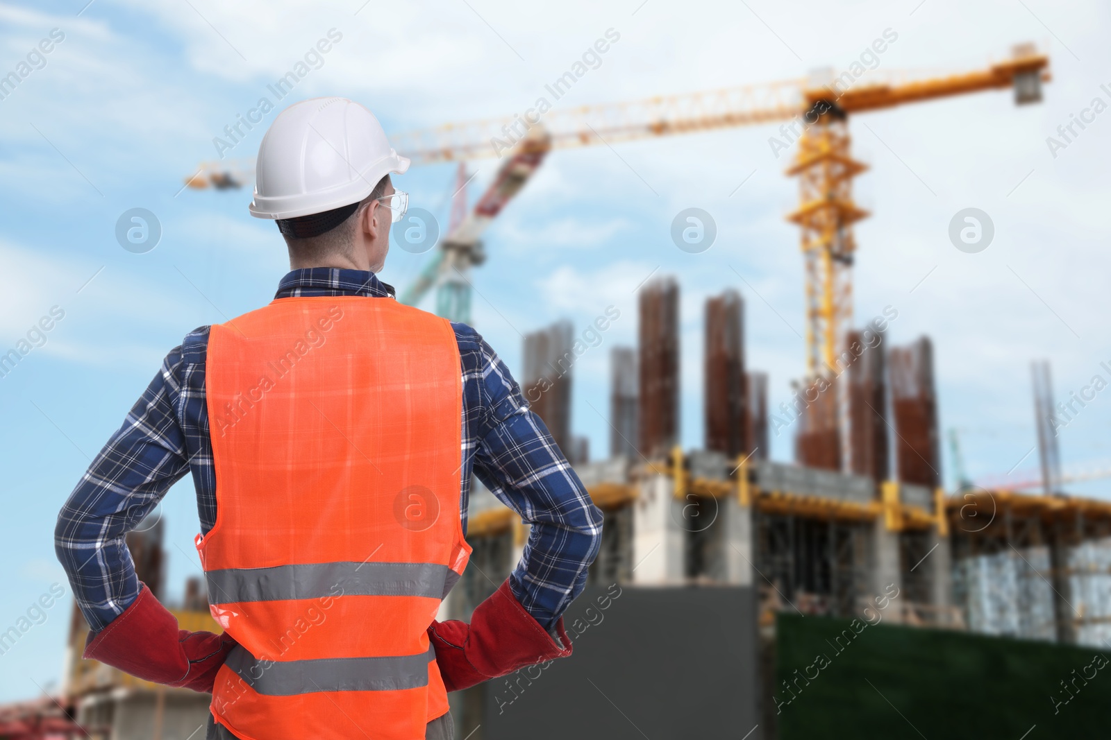 Image of Young man wearing safety equipment at construction site, back view. Space for text