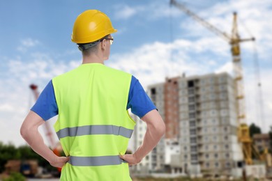 Image of Young man wearing safety equipment at construction site, back view. Space for text