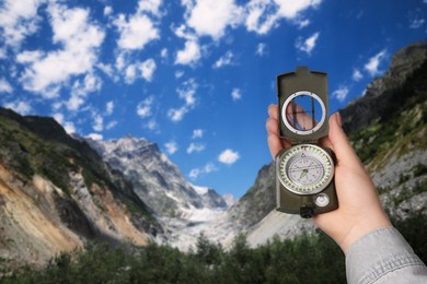 Image of Woman using compass in mountains, closeup. Navigational instrument