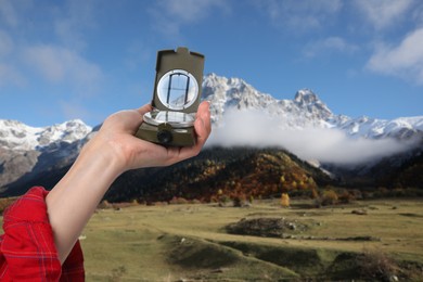 Image of Woman using compass in mountains, closeup. Navigational instrument