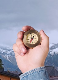 Image of Man using compass in mountains, closeup. Navigational instrument